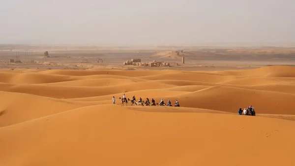 在撒哈拉沙漠之旅期间 有许多游客骑骆驼 有古代遗迹的背景 位于摩洛哥Merzouga — 图库照片