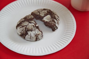 Kırık çikolatalı kurabiye, beyaz bir tabaktaki çatlaklar kırmızı arka planda, yakın planda.