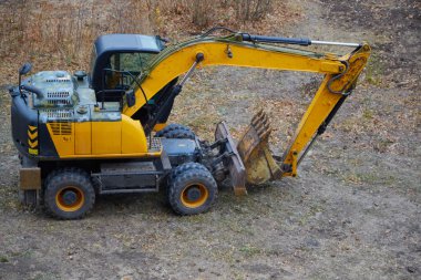 Ready-to-work excavator on a construction site soil plot, backhoe loader on the construction site, excavator with a folded bucket.