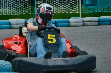 A racer in a helmet driving a rental go-kart on the track, participating in go-karting, go-kart racing.