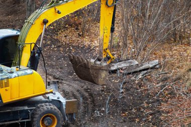 Excavator bucket in front of a construction earth site, beginning of site development.