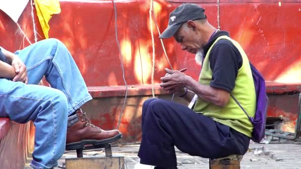 Un vieil homme travaille comme cireur de chaussures . — Video