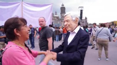 MEXICO CITY 01 / 07 / 19. Meksika başkanının maskesi takan bir adam, Meksika başkanının seçimlerde kazandığı zaferin bir yıl kutlamalarında insanları selamlıyor ve bazı kadınlarla dans ediyor. TAKE3