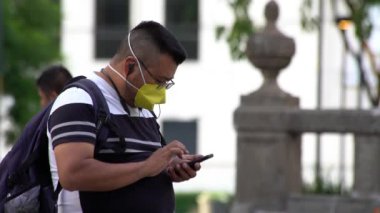 MEXICO ŞEHRİ, Temmuz 2020. Yüz maskesi takan, dinlenen ve parkta cep telefonuyla oynayan bir adam. Yetkililer COVID-19 hakkındaki kısıtlamaları kaldırdıktan sonra, insanlar faaliyetlerine geri dönmeye çalışıyorlar..