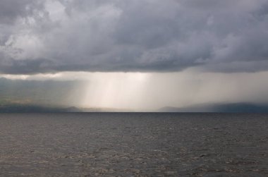 Bulutlar ve yağmur okyanusta bir tropik ada yakın: