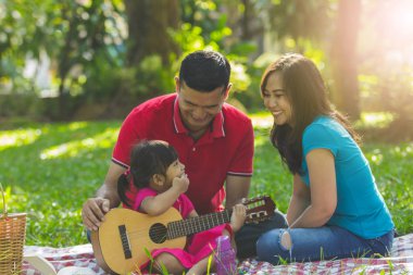 Baba ve anne ve sevimli küçük kızı bir park müzik çalmak
