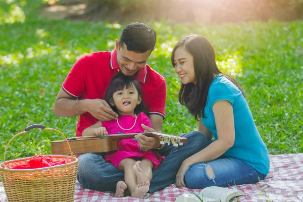 Çok güzel bir aile. Anne, baba ve sevimli kızları piknik üzerinde