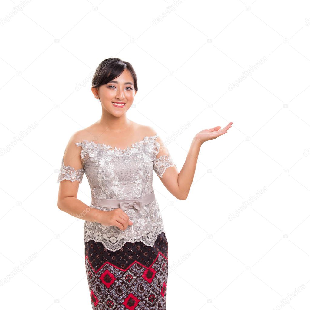 Portrait of beautiful Asian girl in ethnic costume, friendly suggesting or presenting something with her left arm, isolated on white background