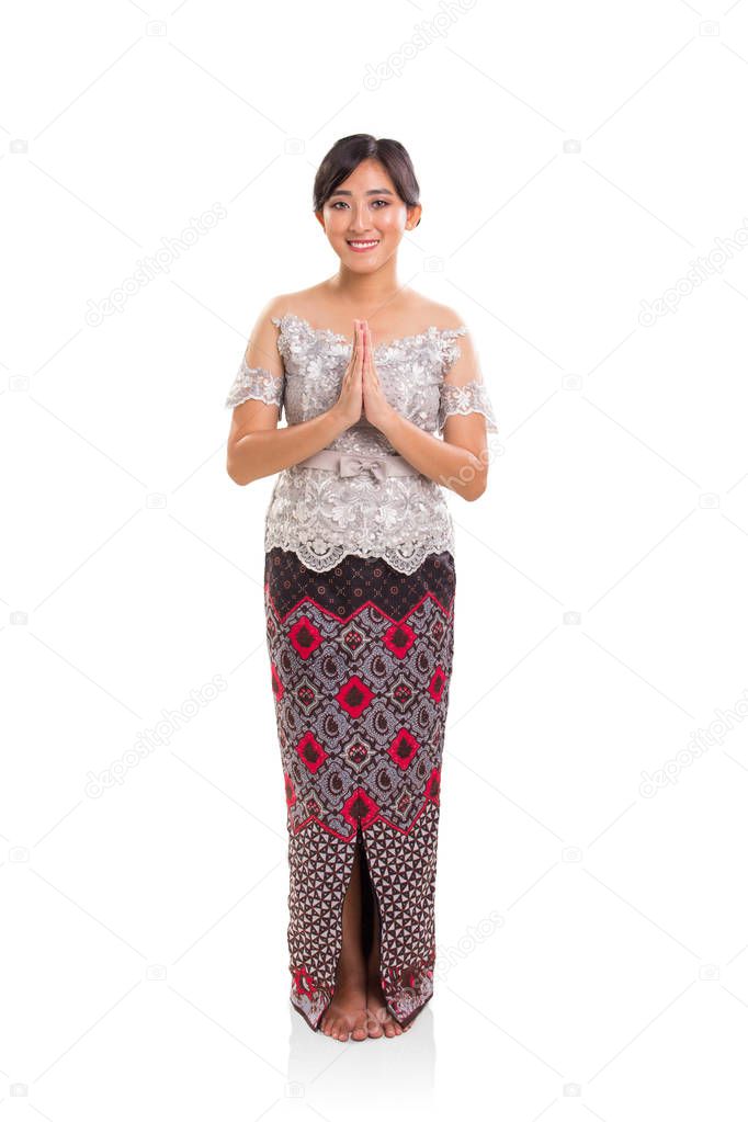 Beautiful Southeast Asian young lady wearing modern ethnic outfits standing with hands clasping in front of her chest. Full body portrait over white background