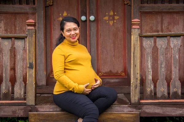 Aziatische etnische vrouw tijdens de zwangerschap zittend op de veranda — Stockfoto