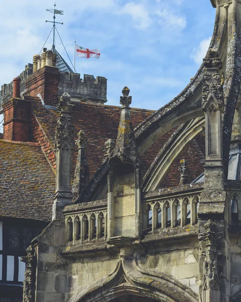 Part of Old Gothic Architecture with Waving English Flag in Back