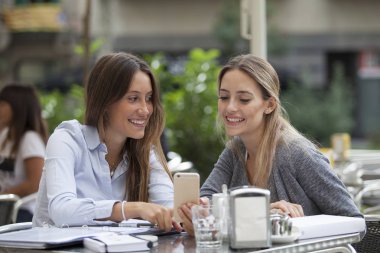 Bir teras bar cep telefonu arıyorum ve gülümseyerek oturan iki kadın
