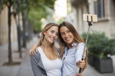 Eğlenceli ve çekici selfie kentsel arka plan üzerinde iki gülümseyen kız orgazm