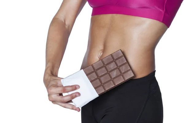 Fitness woman holding chocolate bar. Isolated on white background
