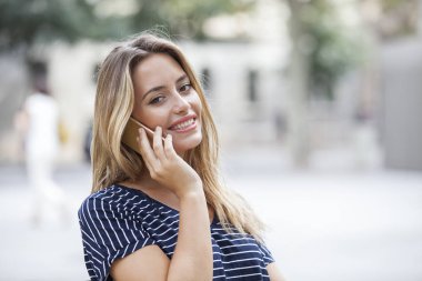 Bir akıllı telefon ile konuşmak ve sokakta duran kamera bakıyor güzel kadın