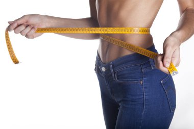 İnce bir kadın beline bir ölçüm bandı tutuyor. Diyet konsepti. Beyaz arka planda yalıtılmış