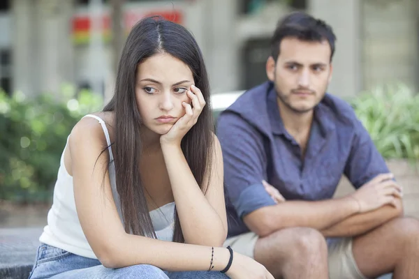 Kavgadan sonra bankta oturan üzgün genç çift. Ayrılma konsepti