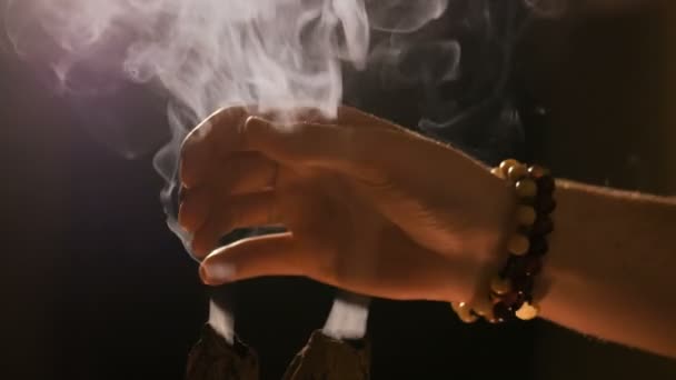 Smoke from incense rises through fingers — Stock Video