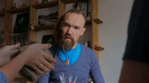Mann zeigt im Töpferatelier, wie man Tonbecher macht — Stockvideo