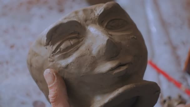 2 постріли. Професійний гончар, що робить обличчя на глиняному кубку зі спеціальним інструментом в керамічній майстерні — стокове відео