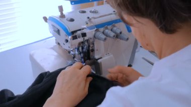 Profesyonel terzi, moda tasarımcısı dikiş makinesiyle elbise dikiyor.
