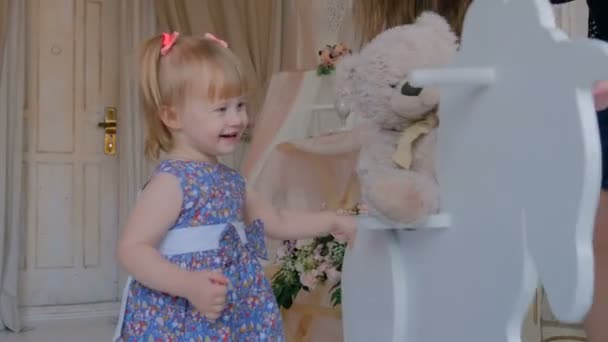 Niña jugando con el caballo mecedora de madera — Vídeos de Stock