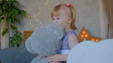 Evde oyuncak ayıyla komik küçük bir kızın portresi. Aile, çocukluk ve eğlence kavramı