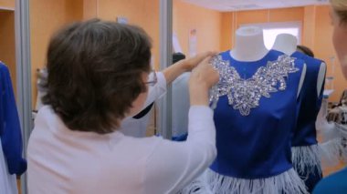 İki moda tasarımcısı yeni manken terzisi elbisesiyle çalışıyor.