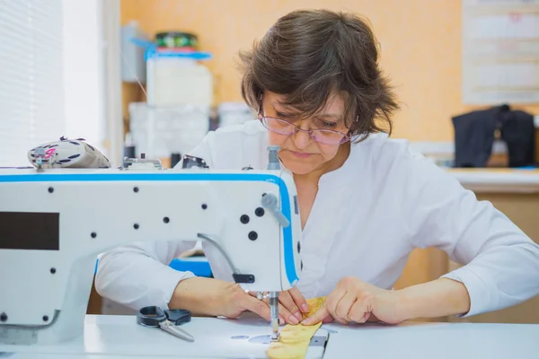 Professional tailor sewing clothes with sewing machine at atelier Stock Picture