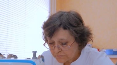 Profesyonel terzi, moda tasarımcısı dikiş makinesiyle elbise dikiyor.