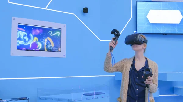 Young woman using virtual reality headset and drawing with special joystick