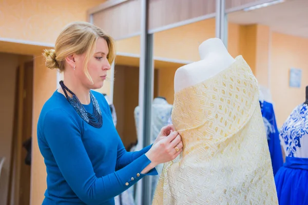 Fashion designer working with new model tailoring dress on mannequin