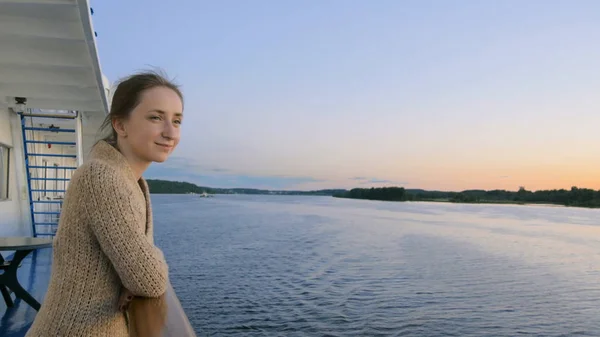 Frau bewundert Landschaft vom Deck des Kreuzfahrtschiffes nach Sonnenuntergang Stockbild