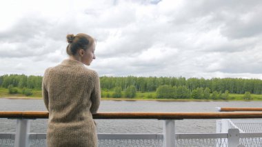 Cruise gemi güverte üzerinde duran ve nehir ve manzara bakarak genç kadın