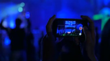 Akıllı telefonlu canlı müzik konserinin görüntülerini kaydeden eller.