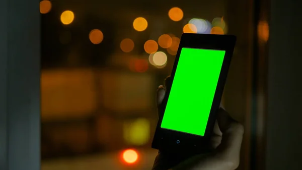Woman looking at smartphone with green screen