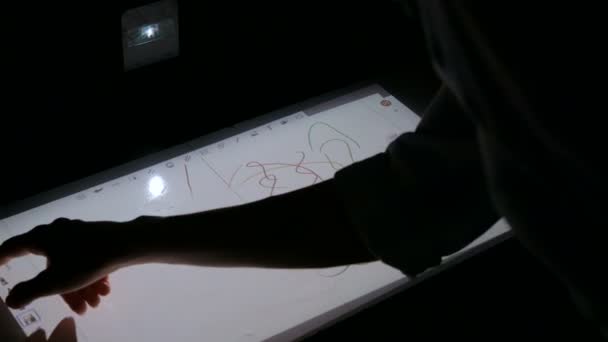 Женщина использует интерактивный сенсорный проектор для рисования на выставке — стоковое видео
