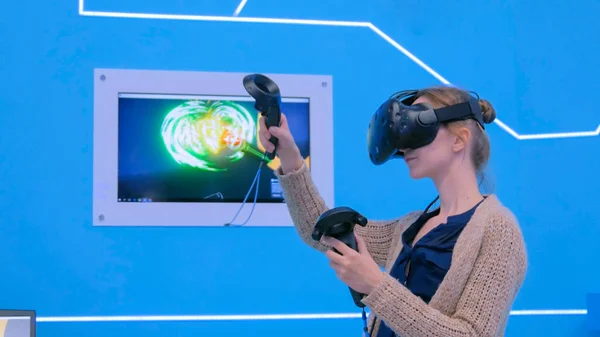 Young woman using virtual reality headset and drawing with special joystick