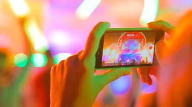 Akıllı telefonlu canlı müzik konserinin görüntülerini kaydeden eller.