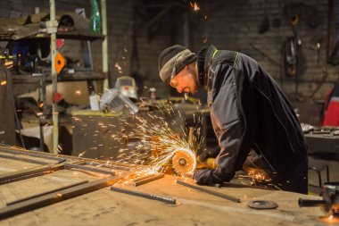 Demirci el testeresiyle metal kesiyor.