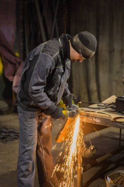 Demirci el testeresiyle metal kesiyor.