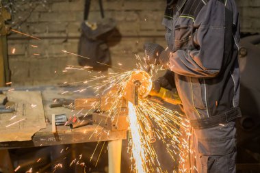 Demirci el testeresiyle metal kesiyor.