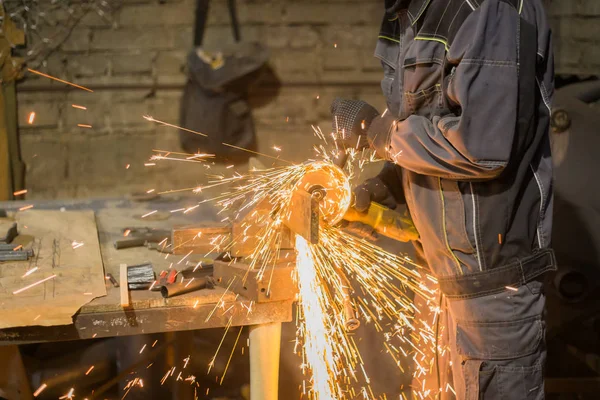 Demirci el testeresiyle metal kesiyor.