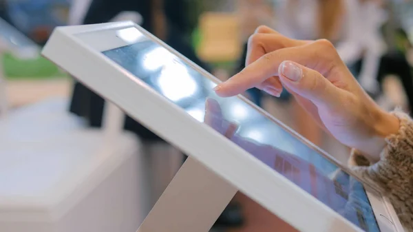 Şehir sergisinde etkileşimli dokunmatik ekran kullanan kadın