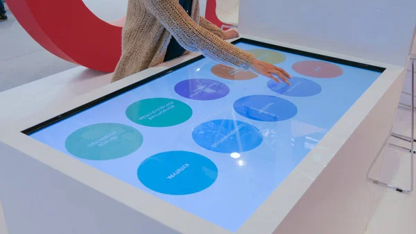 Modern teknoloji sergisinde etkileşimli dokunmatik ekran kullanan kadın