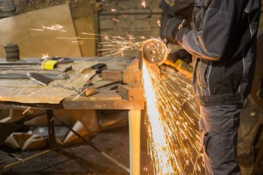 Demirci el testeresiyle metal kesiyor.