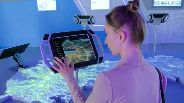 Woman using interactive touchscreen display at modern technology exhibition