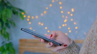 Evde dikey siyah akıllı telefon kullanan bir kadın