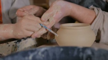 Potter çömlek atölyesinde seramik ile nasıl çalışılacağını gösteriyor.