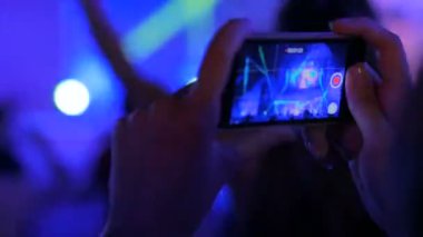 Akıllı telefonlu canlı müzik konserinin görüntülerini kaydeden eller.